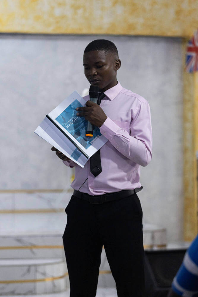 A young church leader preaching from an SGC Leadership Handbook